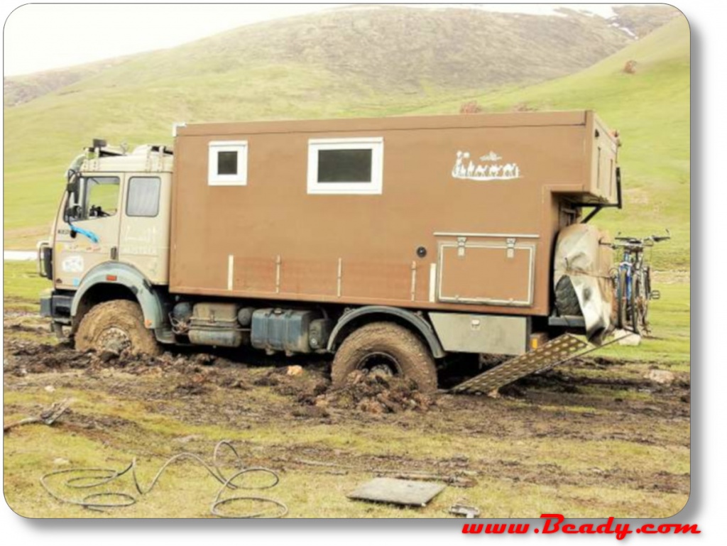 overland truck stuck in mud on green flields