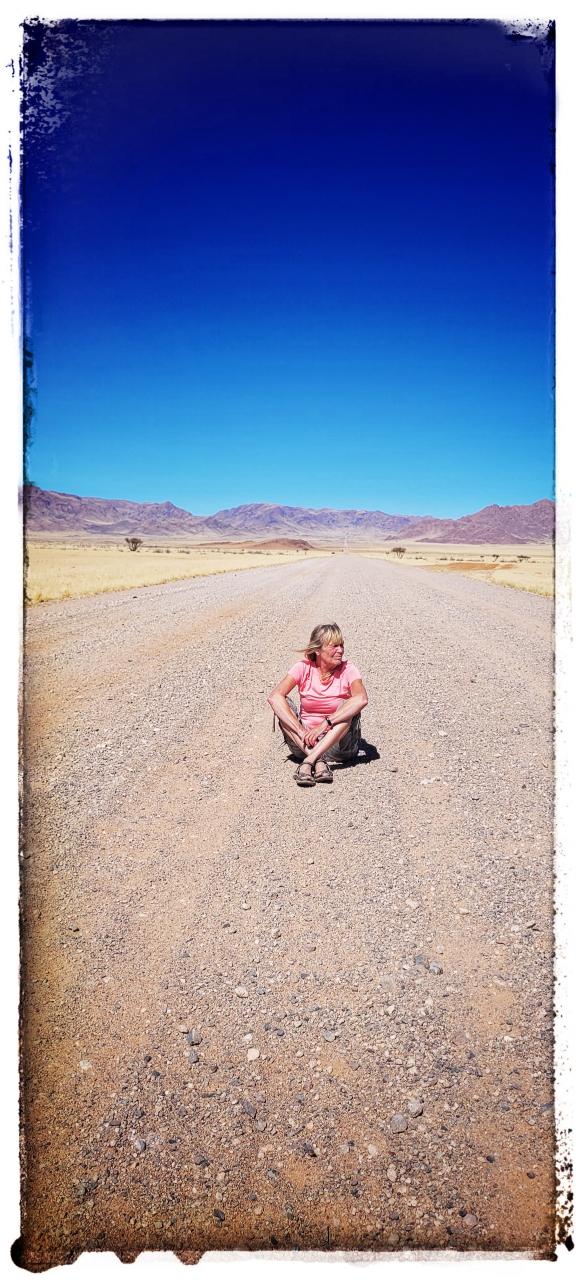 woman sat in deserted Namibian gravel road in sunshine